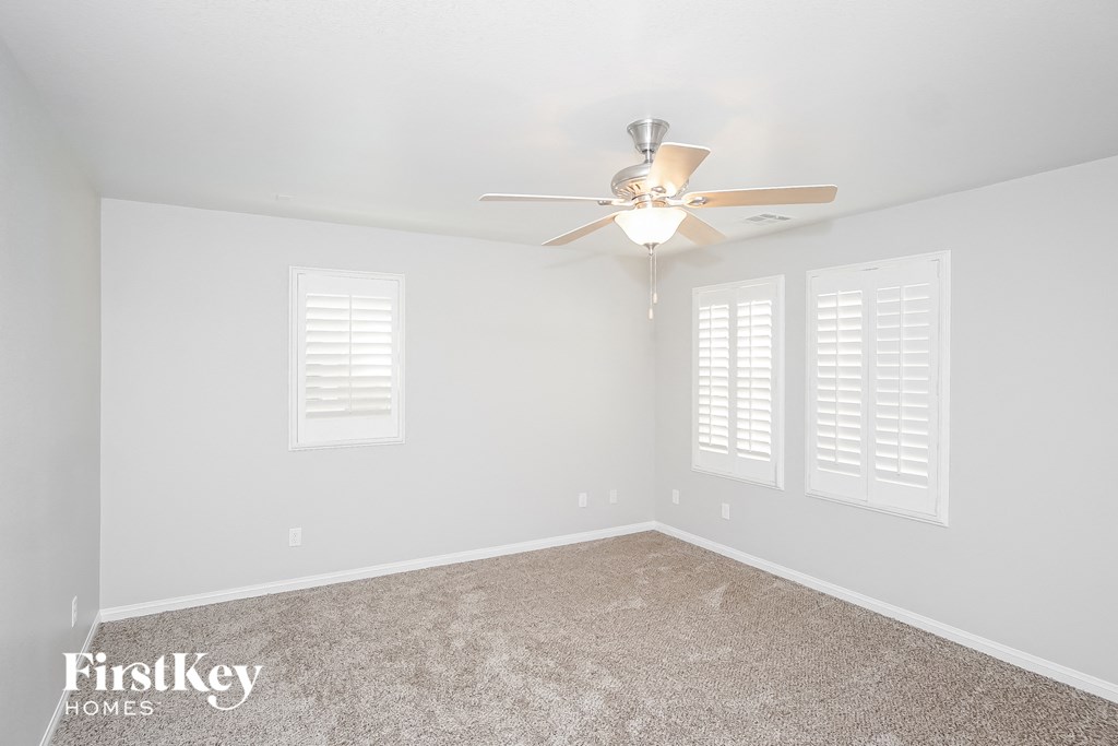 a bedroom with white walls and a ceiling fan