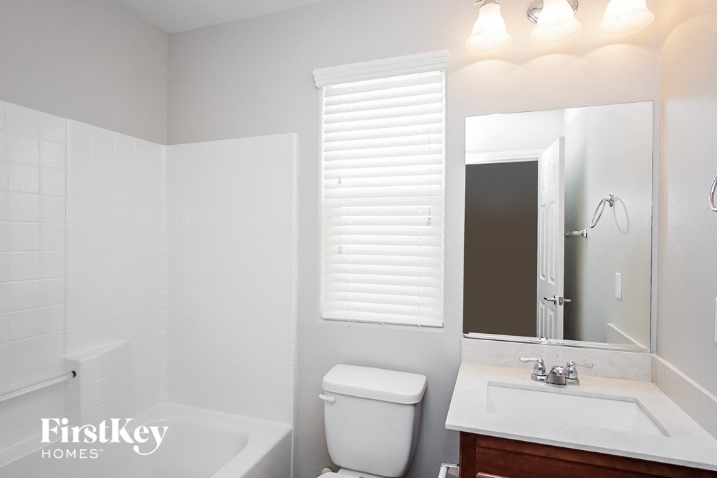a bathroom with a toilet sink and mirror and a tub