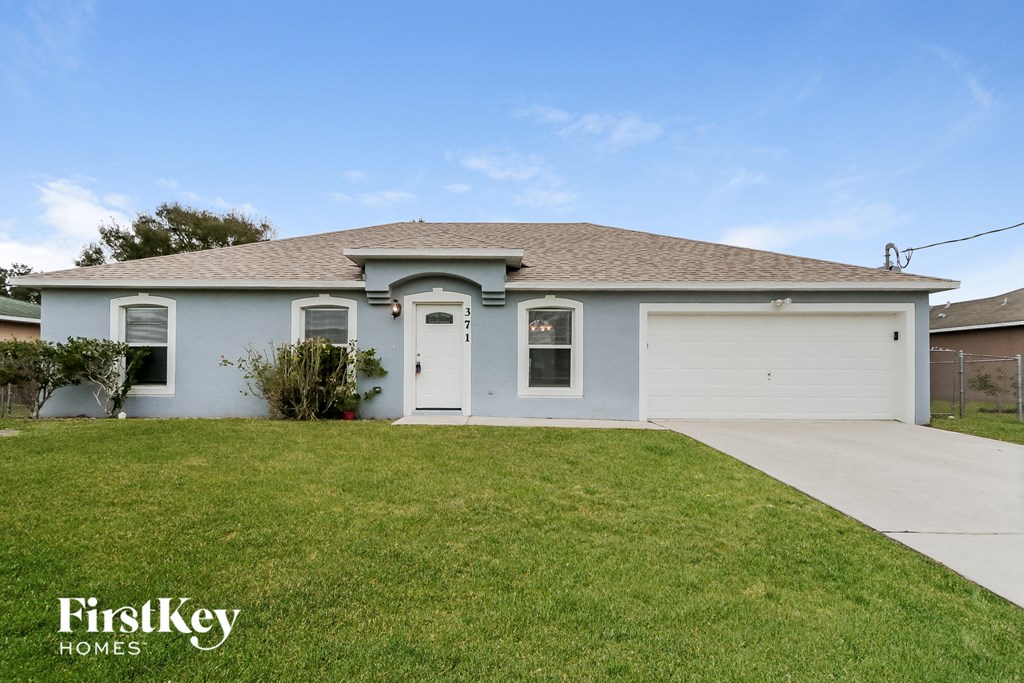 A house with a garage and a driveway in front of it.