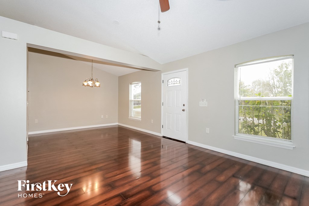 A spacious room with wooden floors and a ceiling fan.