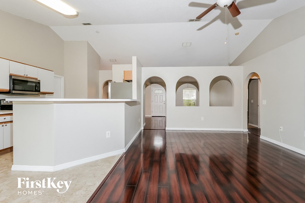 A spacious living room with a wood floor and a ceiling fan.
