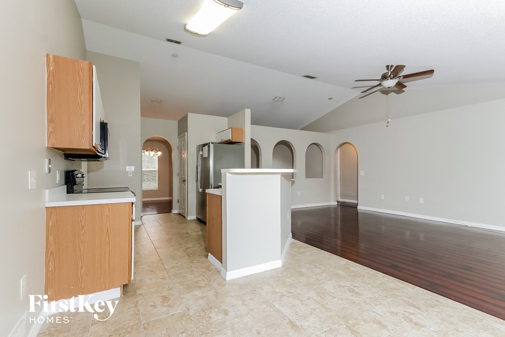 A spacious living room with a kitchen area in the background.