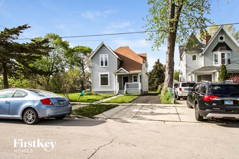A blue car is parked in front of a house with the words "FirstKey HOMES" on the bottom left corner of the image.