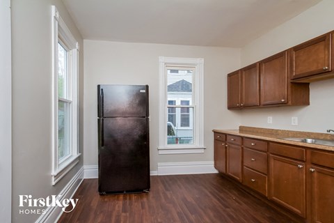 A kitchen with a black fridge and wooden cabinets.