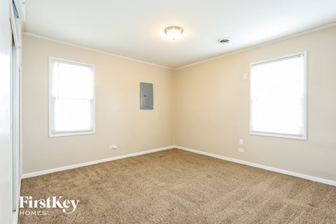 the living room of a home with carpet and two windows