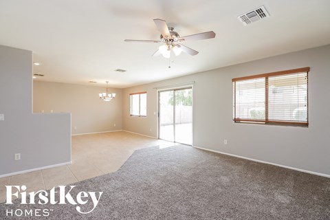 an empty living room with a ceiling fan and a window