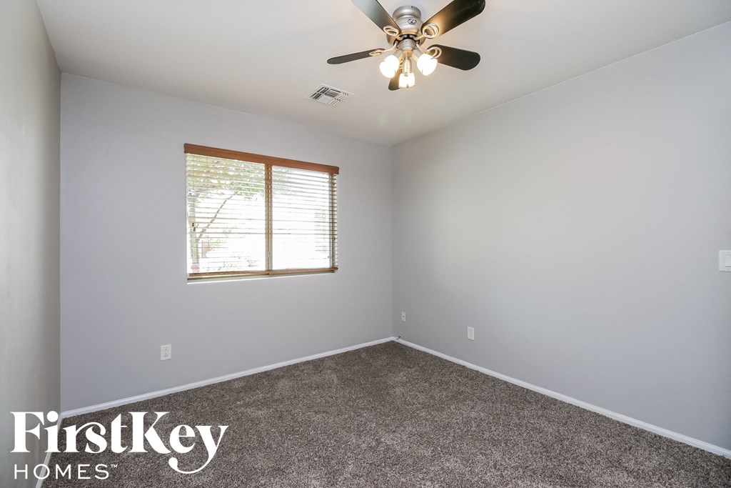 an empty room with a ceiling fan and a window