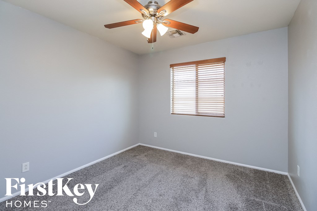 an empty room with a ceiling fan and a window