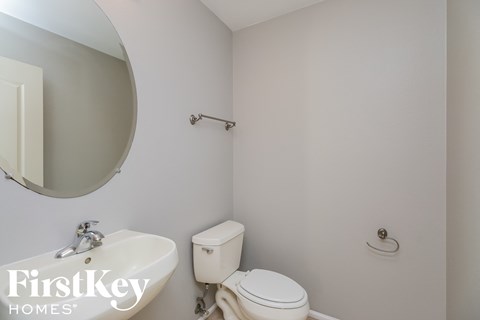 a white bathroom with a white toilet and a sink and a mirror