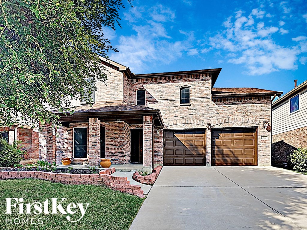 a brick house with brown garage doors and a sidewalk