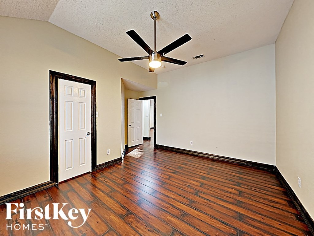 an empty living room with hard wood floors and a ceiling fan