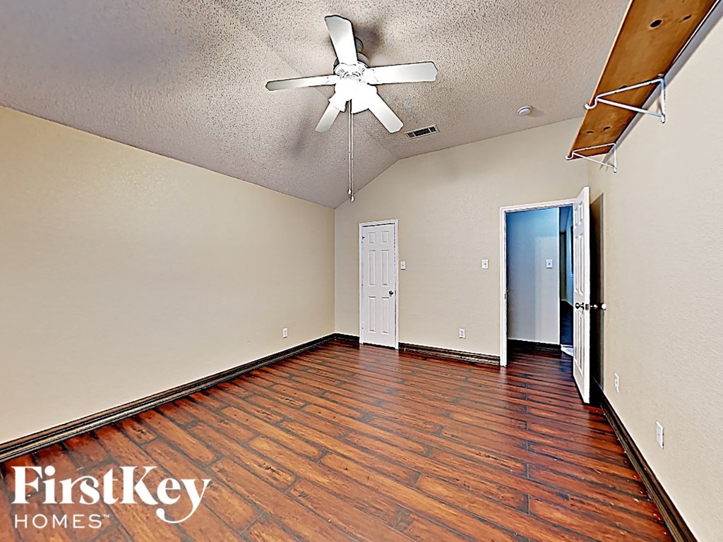 an empty living room with wood floors and a ceiling fan