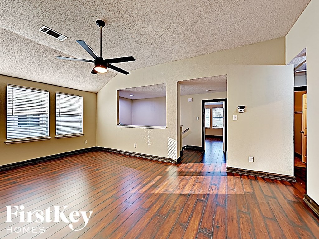 an empty living room with hard wood floors and a ceiling fan