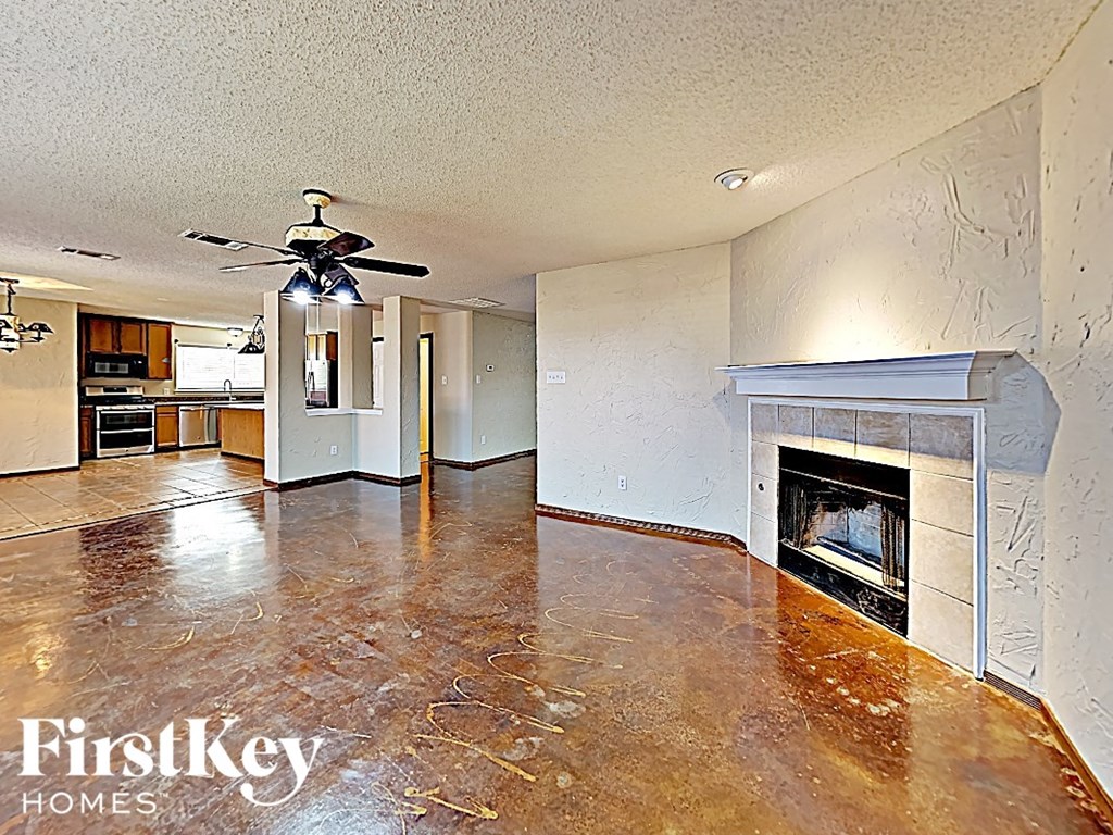an empty living room with a fireplace and a ceiling fan