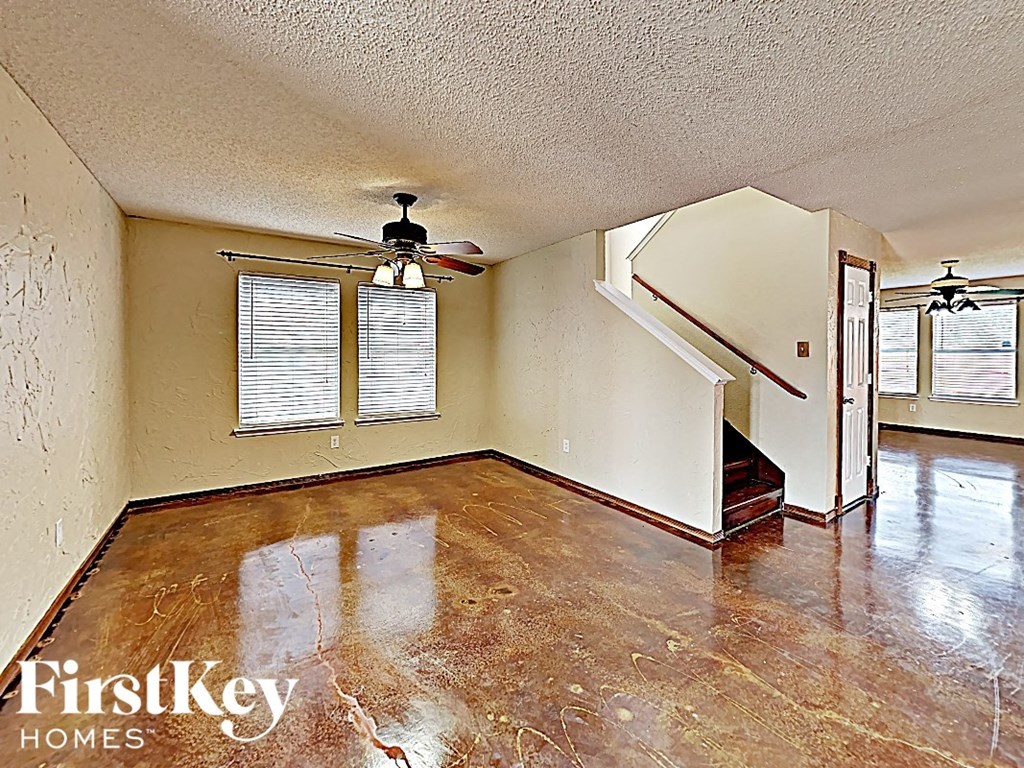an empty living room with white walls and a ceiling fan