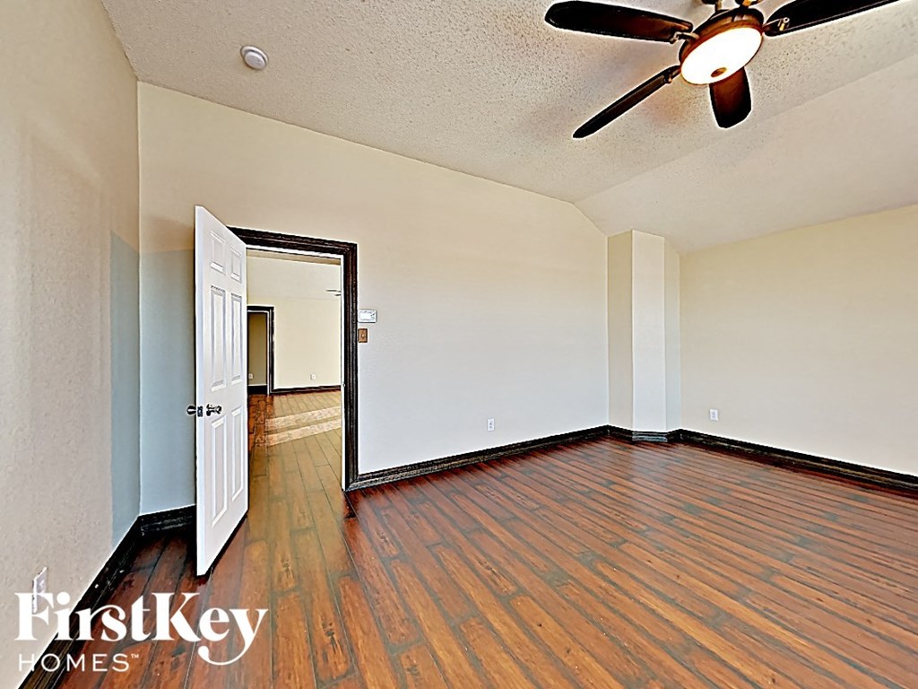 an empty living room with wood flooring and a ceiling fan