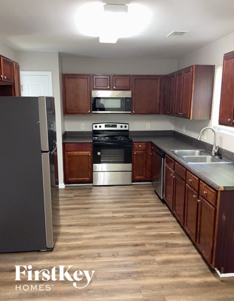 A kitchen with wooden cabinets and a stainless steel refrigerator.