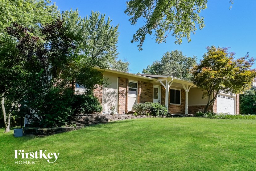 a small brick house with a grassy lawn and trees