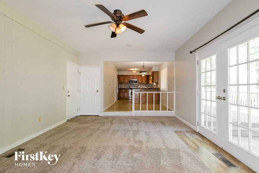 an empty living room with a ceiling fan and a kitchen