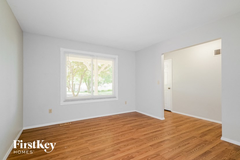 the living room of a house with white walls and wood floors