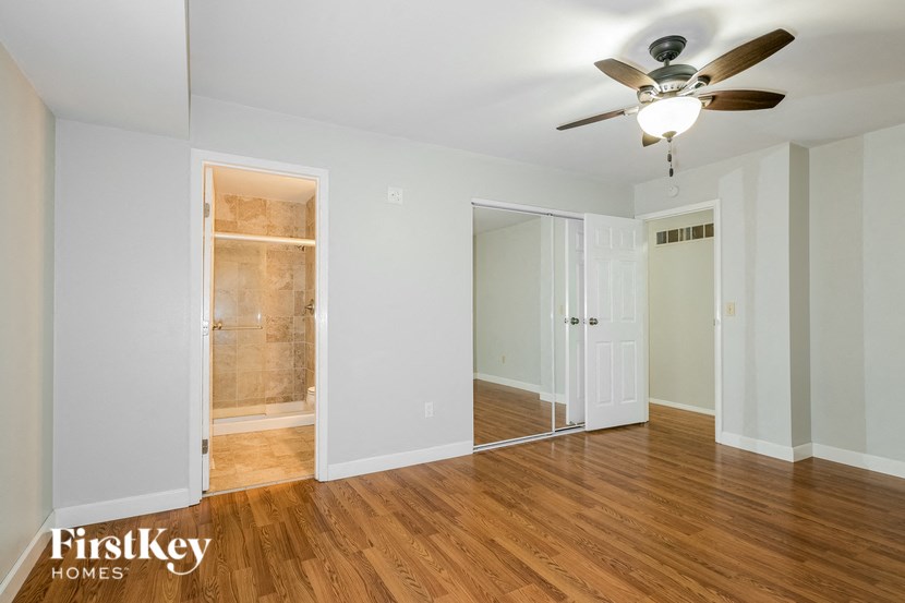 a bedroom with a ceiling fan and a mirrored closet