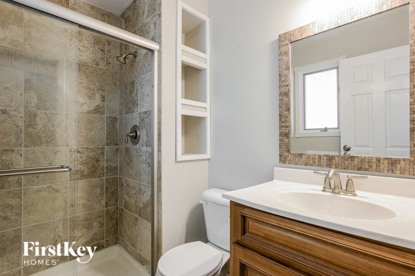 a bathroom with a toilet sink and shower and a mirror