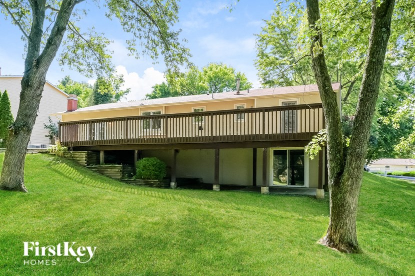 the side of a house with a lawn and trees
