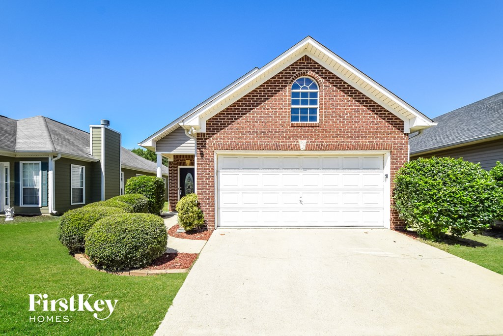 a white garage door in front of a brick house