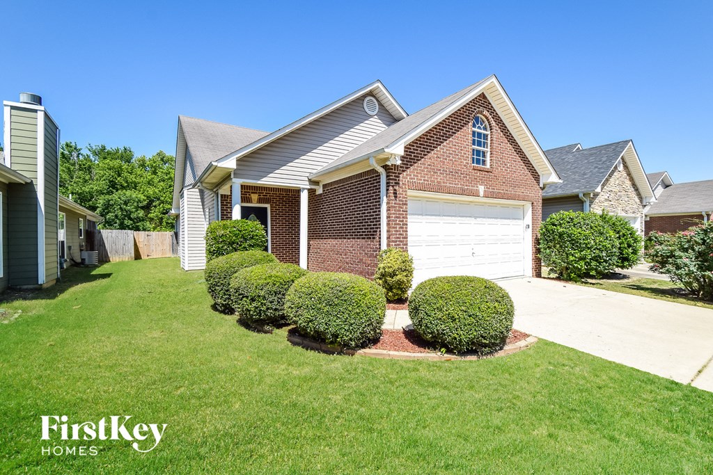 a brick house with a white garage door in front of a lawn