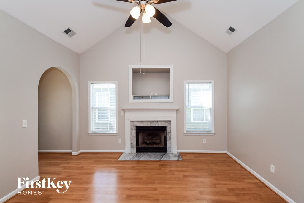 an empty living room with a fireplace and a ceiling fan
