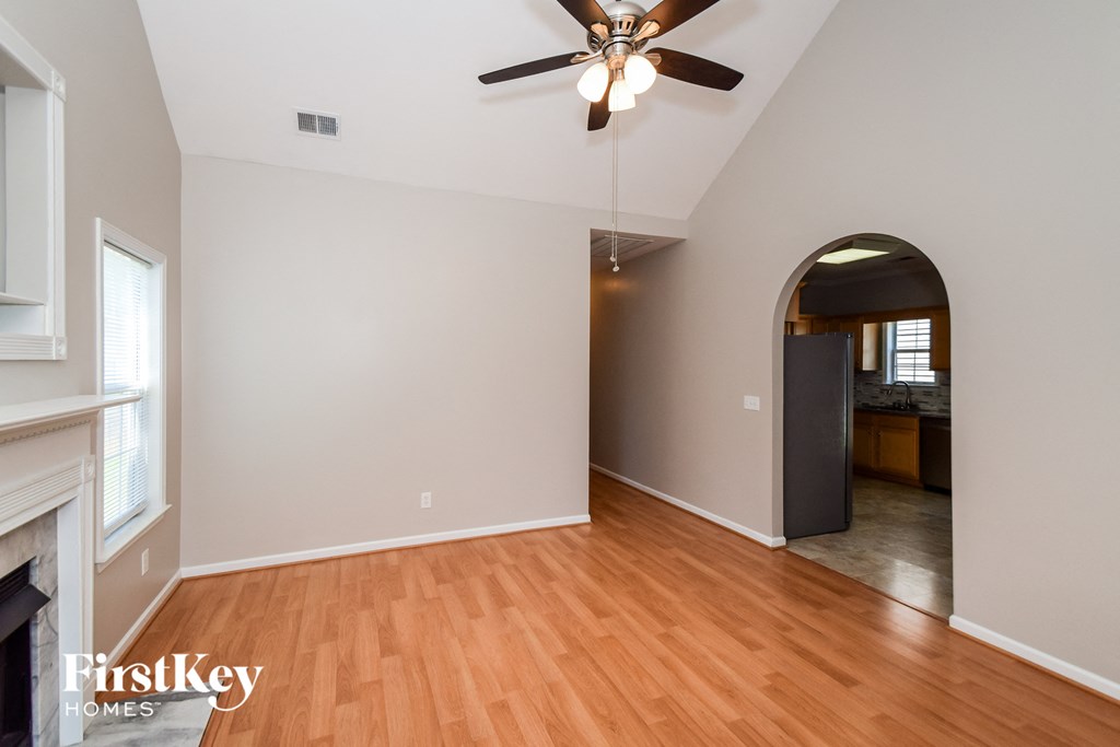 an empty living room with wood flooring and a ceiling fan