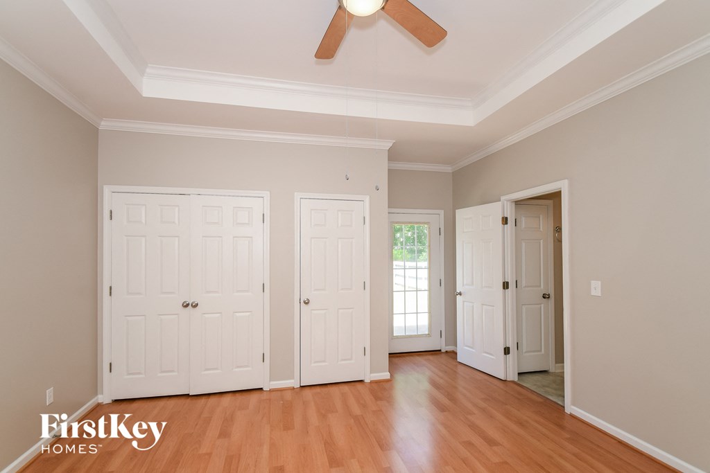 a bedroom with three closets and a ceiling fan
