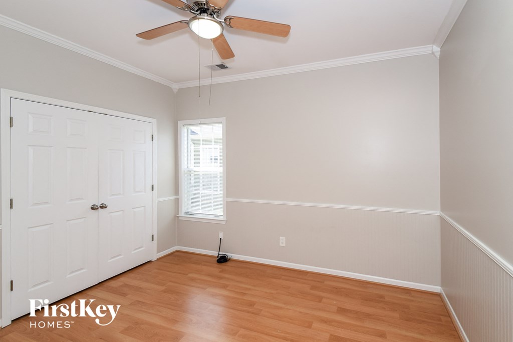 a bedroom with wood floors and a ceiling fan