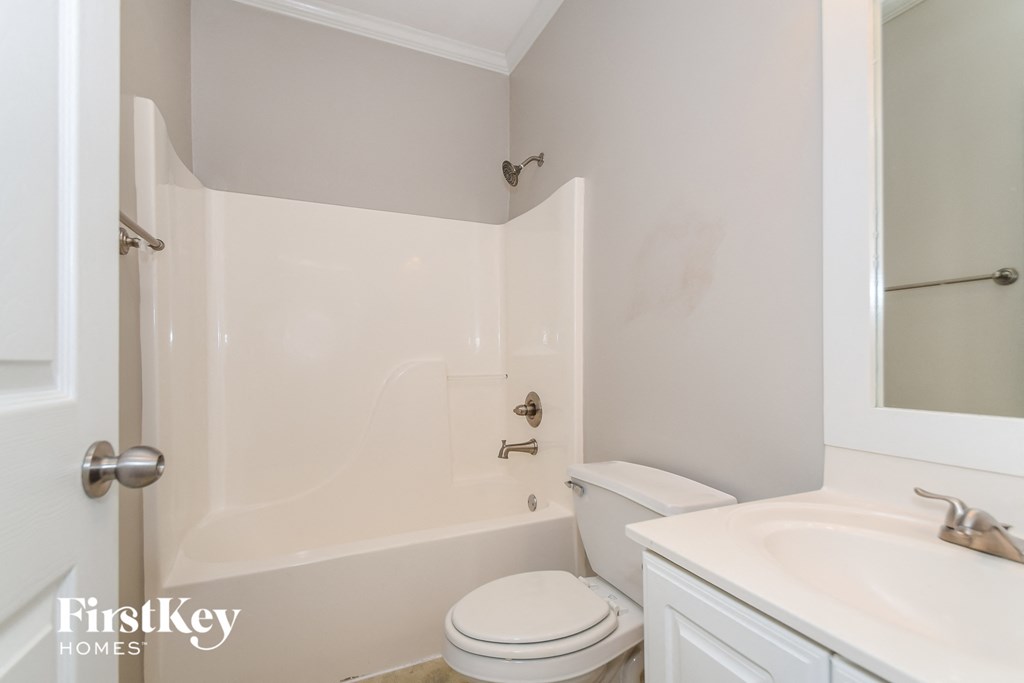 a white bathroom with a white toilet and tub and a sink