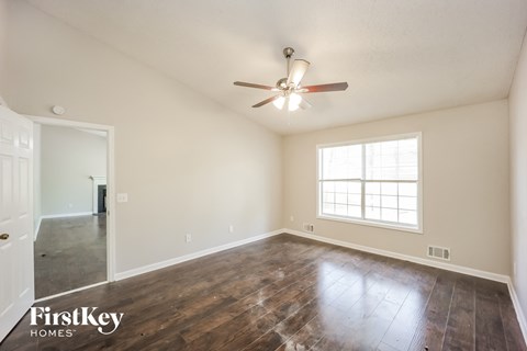 the spacious living room with hardwood flooring and a ceiling fan