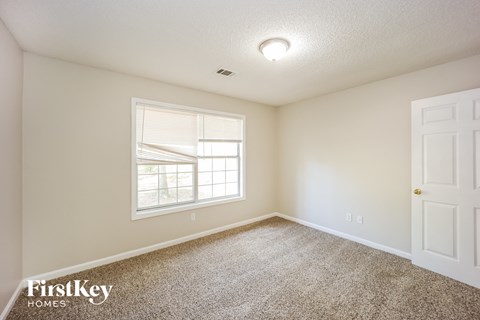 a bedroom with carpet and a window and a white door