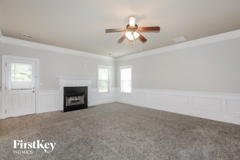 A spacious room with a fireplace and a ceiling fan.