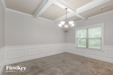 A well-lit room with a chandelier and a carpeted floor.