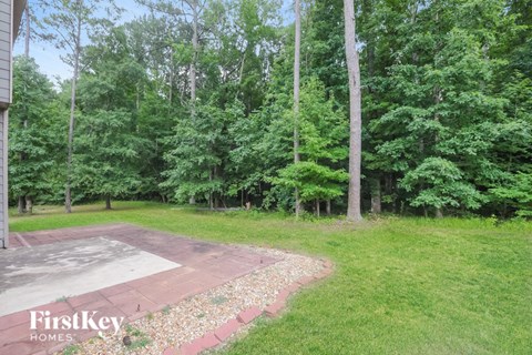 A backyard with a concrete patio and a grassy area.