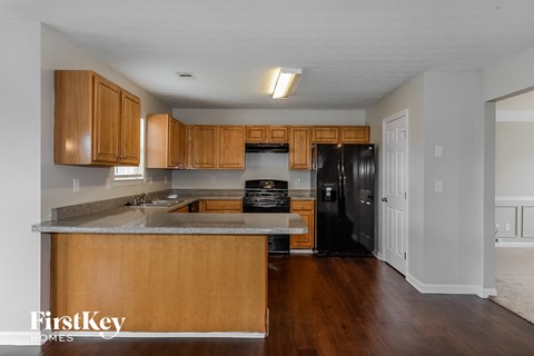 A kitchen with wooden cabinets and a black fridge.