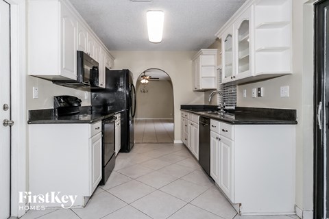 a kitchen with white cabinets and black counter tops