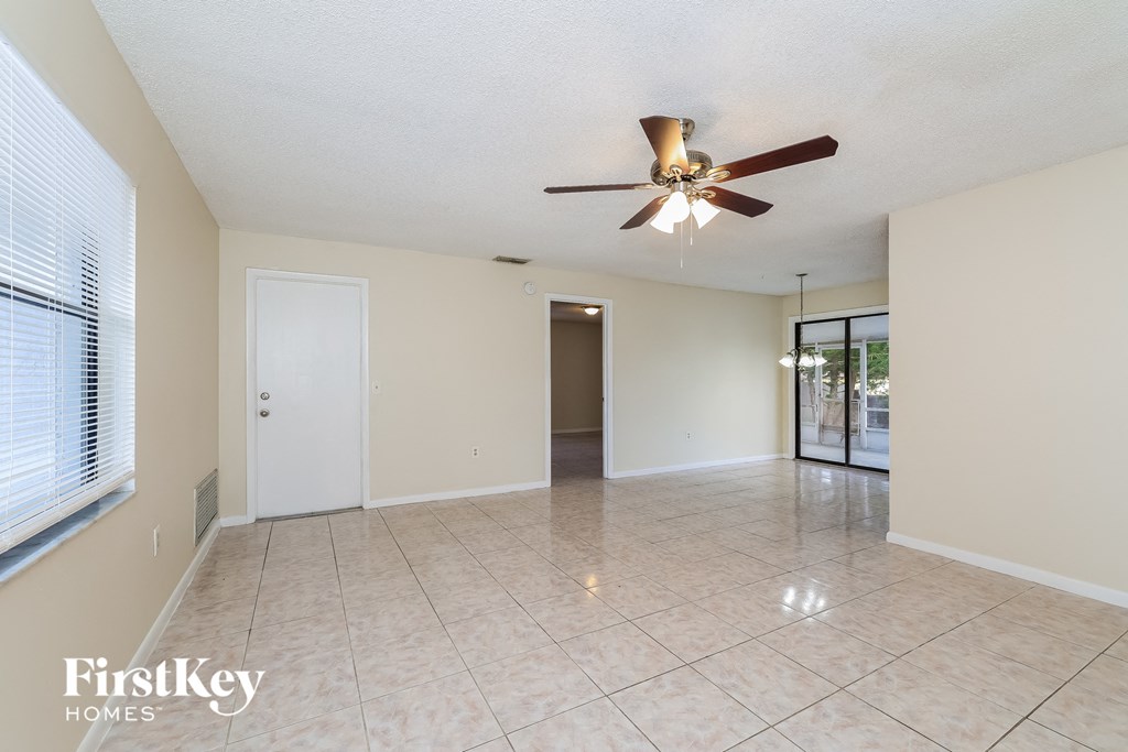 A spacious room with a ceiling fan and tiled flooring.