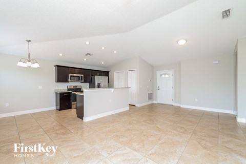 A spacious kitchen and living room with a tiled floor and a chandelier.