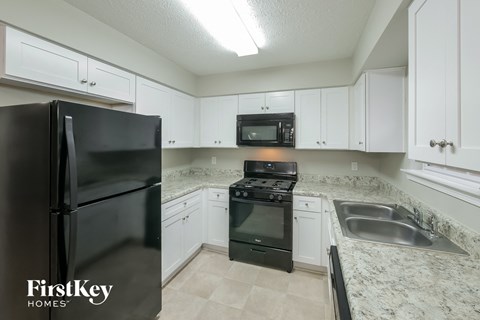 a kitchen with white cabinets and black appliances