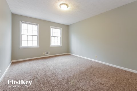 the master bedroom with carpet and two windows
