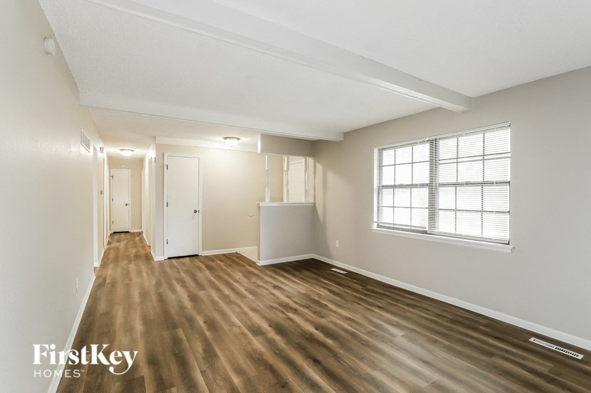 the living room and dining room of an empty house with wood flooring