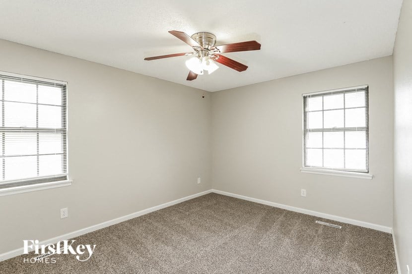 a bedroom with a ceiling fan and two windows