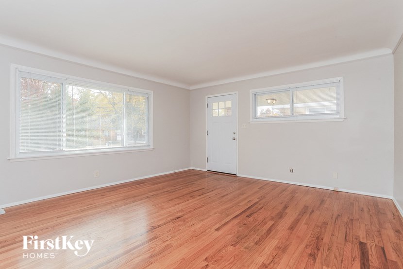 the living room of a home with wood floors and white walls