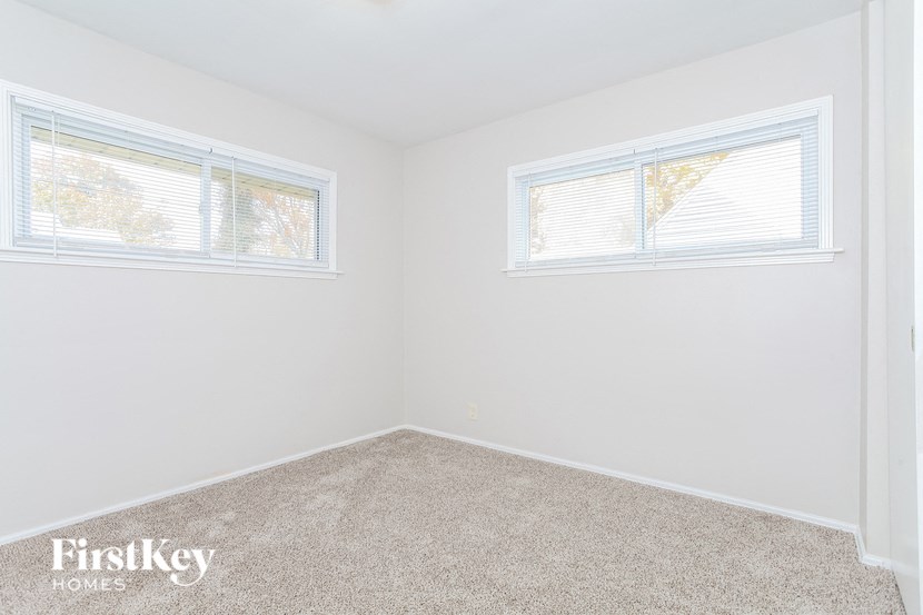 the bedroom of a home with carpet and two windows