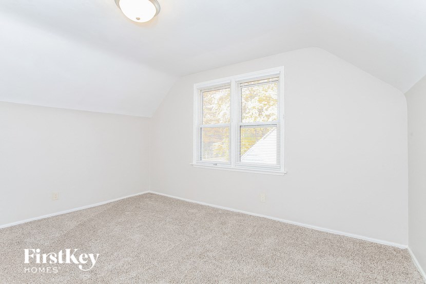 an empty bedroom with a window and carpet